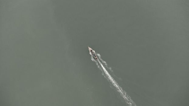 Aerial view from a drone of Thai traditional longtail fishing boats sailing in the sea. Top view of a fast moving fishing boat in the ocean.