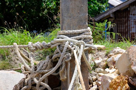 Mooring rope with a knotted end is tied around a cement pole on the pier. Nautical mooring rope. The concept of mooring and water transportation