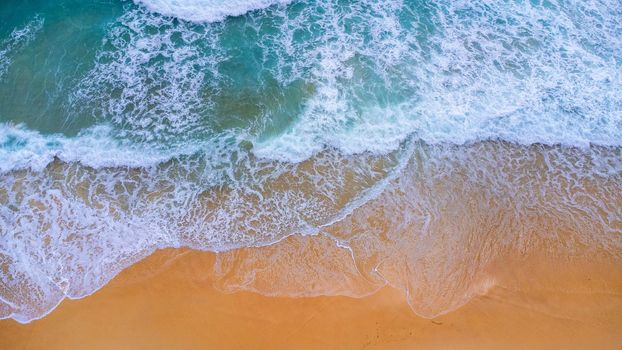 Beautiful sea waves and white sand beach in the tropical island. Soft waves of blue ocean on sandy beach background from top view from drones. Concept of relaxation and travel on vacation.