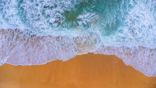 Beautiful sea waves and white sand beach in the tropical island. Soft waves of blue ocean on sandy beach background from top view from drones. Concept of relaxation and travel on vacation.