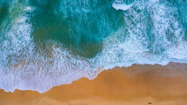 Beautiful sea waves and white sand beach in the tropical island. Soft waves of blue ocean on sandy beach background from top view from drones. Concept of relaxation and travel on vacation.