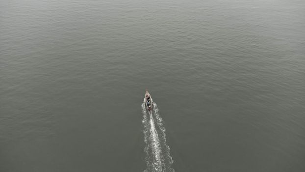 Aerial view from a drone of Thai traditional longtail fishing boats sailing in the sea. Top view of a fast moving fishing boat in the ocean.