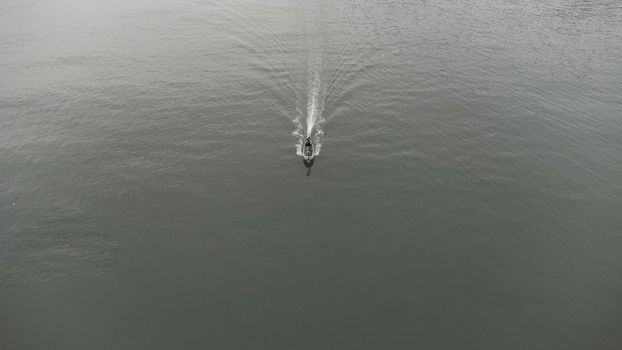 Aerial view from a drone of Thai traditional longtail fishing boats sailing in the sea. Top view of a fast moving fishing boat in the ocean.