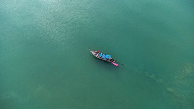 Aerial view from a drone of Thai traditional longtail fishing boats sailing in the sea. Top view of a fishing boat in the ocean.