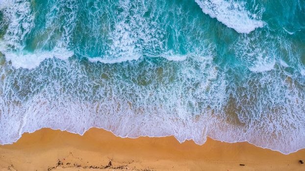 Beautiful sea waves and white sand beach in the tropical island. Soft waves of blue ocean on sandy beach background from top view from drones. Concept of relaxation and travel on vacation.