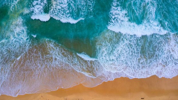 Beautiful sea waves and white sand beach in the tropical island. Soft waves of blue ocean on sandy beach background from top view from drones. Concept of relaxation and travel on vacation.