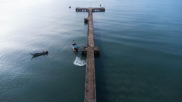 Aerial view from a drone of a pier in a tropical sea. A lot of Thai traditional longtail fishing boats in the sea.