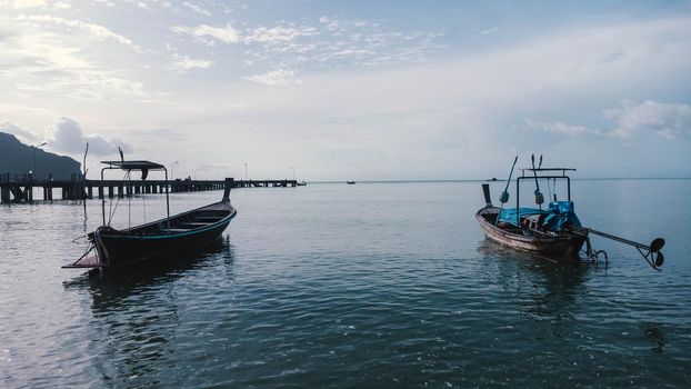 Beautiful scenery of fishing boats at the shore at low tide. A lot of Thai traditional longtail fishing boats in the tropical sea. Pier of the villagers on the southern island of Thailand.