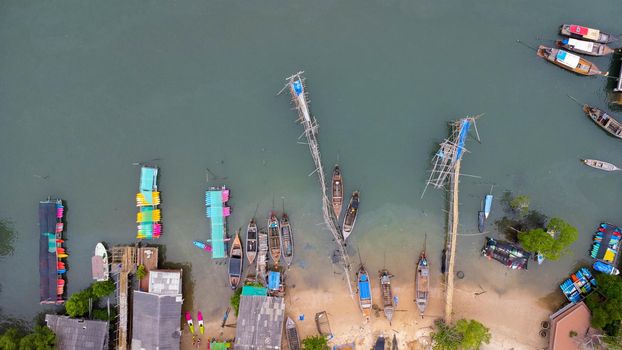 Aerial view from a drone of a pier in a tropical sea. A lot of Thai traditional longtail fishing boats in the sea.