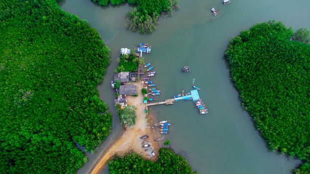 Aerial view of Thai traditional longtail fishing boats at the pier in Phang Nga Bay in the Andaman Sea, Thailand. Top view of many fishing boats floating in the sea among mangrove forest.