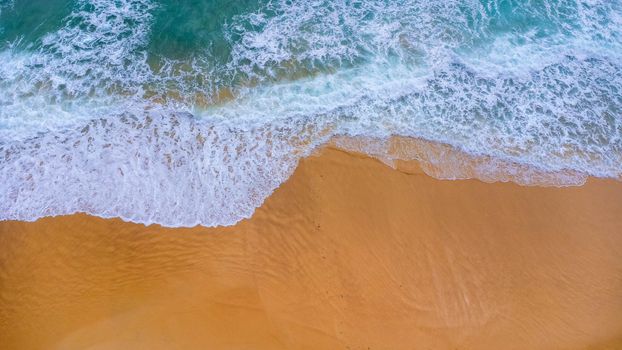 Beautiful sea waves and white sand beach in the tropical island. Soft waves of blue ocean on sandy beach background from top view from drones. Concept of relaxation and travel on vacation.