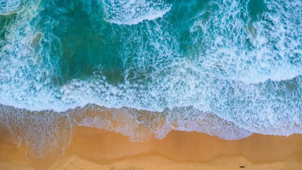 Beautiful sea waves and white sand beach in the tropical island. Soft waves of blue ocean on sandy beach background from top view from drones. Concept of relaxation and travel on vacation.