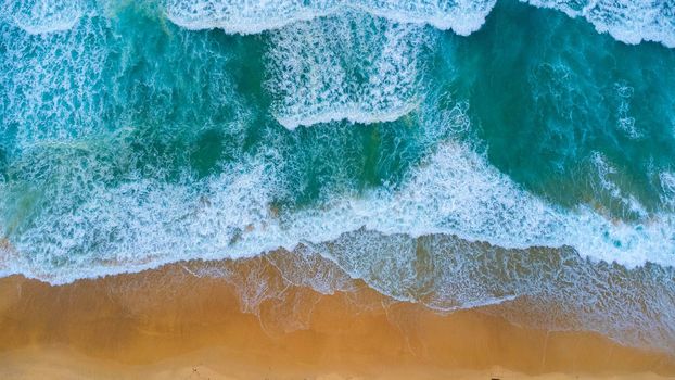 Beautiful sea waves and white sand beach in the tropical island. Soft waves of blue ocean on sandy beach background from top view from drones. Concept of relaxation and travel on vacation.