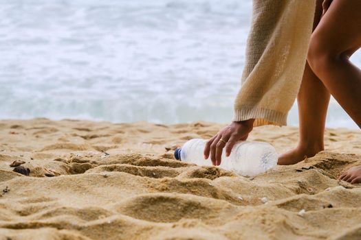 Woman cleaning plastic on the beach. People voluntarily clean nature from plastic. Concept of plastic pollution and environmental problems