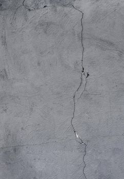 Abstract texture from a wall covered in gray plaster with a large crack.