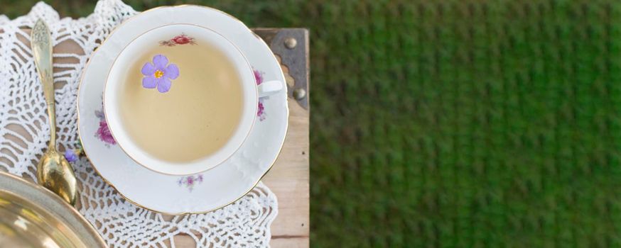 porcelain cup with tea and flower floats in tea, vintage still life, top view, bunner ,High quality photo