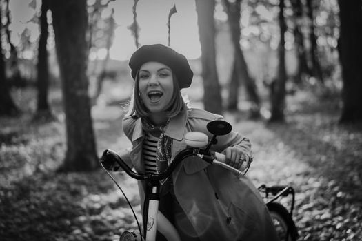 Beautiful black and white portrait of young smiling woman in french beret cycling alone in park. Sunny day in forest. Trendy lady on vintage bicycle, healthy lifestyle, aesthetic scene. High quality