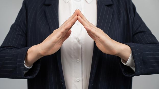 Business woman in a suit holding her hands in the shape of a house