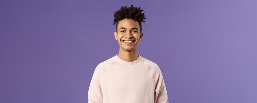 Close-up portrait of cheerful young hipster guy with dreads, smiling optimistic and delighted, standing purple background, having lucky good day, express positivity and joy.