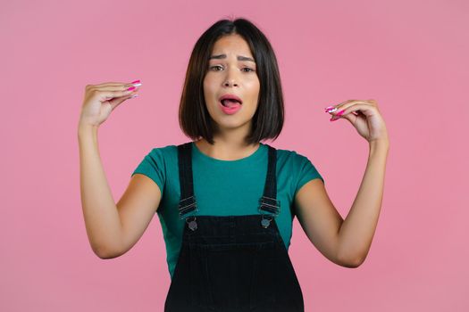 Cute girl showing bla-bla-bla gesture with hands and rolling eyes isolated on pink background. Empty promises, blah concept. Lier