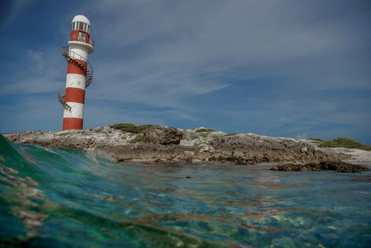 Lighthouse on a rocky shore in Cancun. Clear sky and blue sea.