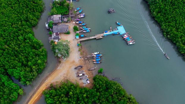 Aerial view of Thai traditional longtail fishing boats at the pier in Phang Nga Bay in the Andaman Sea, Thailand. Top view of many fishing boats floating in the sea among mangrove forest.