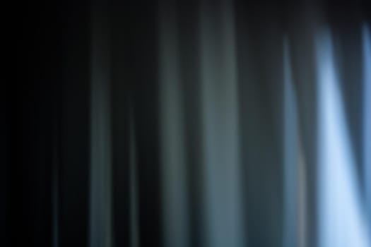 Soft blur of a curtain in dark blue tones with gaps. Wave abstraction. Background. Backdrop