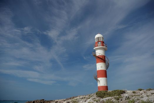 Lighthouse on a rocky shore in Cancun. Clear sky and blue sea.