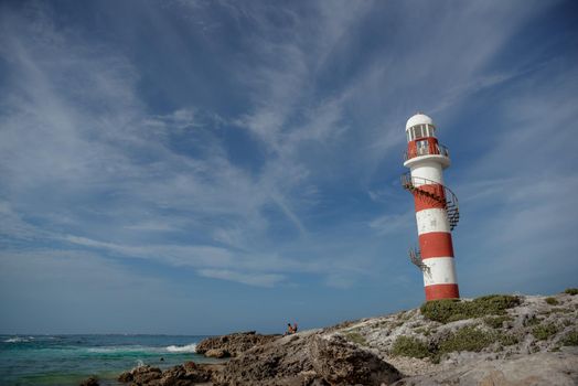 Lighthouse on a rocky shore in Cancun. Clear sky and blue sea.