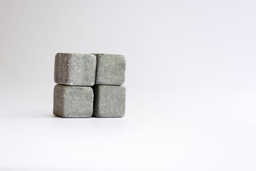 Four whiskey stones close up one above the other on a white gray background