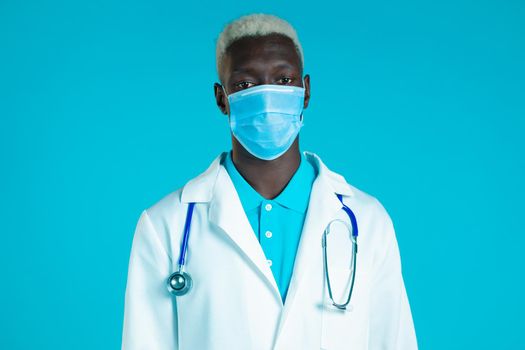 Portrait of african doctor in professional medical coat and mask. Doc man isolated on blue background