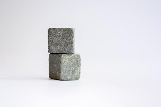 Two stone cubes one above the other. Whiskey stones on a white background.