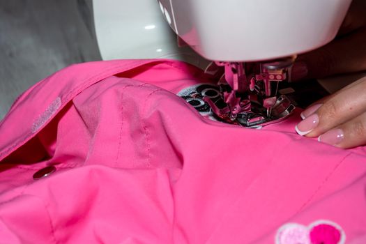 Mom sews a jacket for the child. Woman behind a sewing machine.