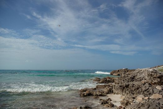 The coastline of the Caribbean Sea with white sand and rocks in Cancun.