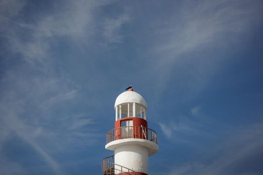 Lighthouse on a rocky shore in Cancun. Clear sky and blue sea.