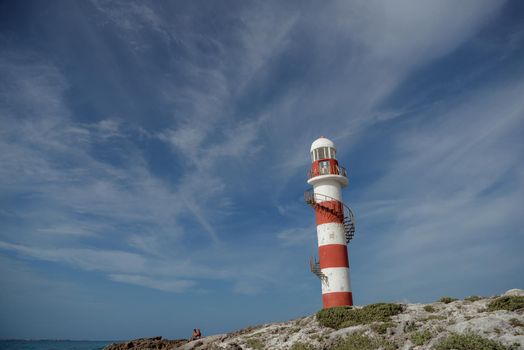 Lighthouse on a rocky shore in Cancun. Clear sky and blue sea.