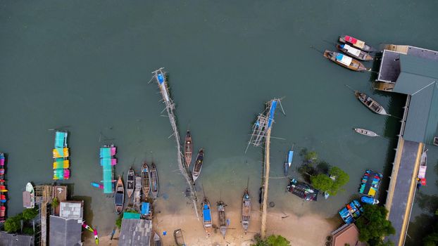Aerial view from a drone of a pier in a tropical sea. A lot of Thai traditional longtail fishing boats in the sea.