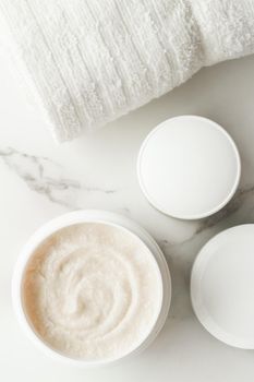 Scrub and exfoliating cream products on a marble, flatlay - skincare and body care, luxury spa and clean cosmetic concept. Health and beauty of your skin