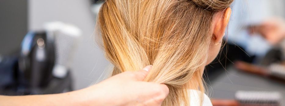 Close up of hands of female hairdresser styling hair of a blonde woman in a hair salon