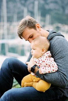 Dad with a child on his knees sits on the green grass. High quality photo