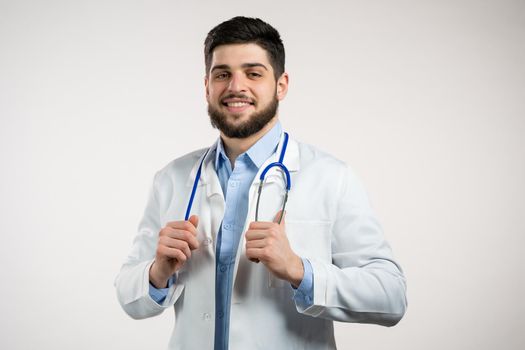 Portrait of cheerful doctor in professional medical coat. Man bearded doc isolated on white background. Medical staff concept. High quality photo