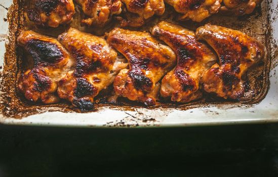 appetizing baked chicken wings in a baking sheet, top view.