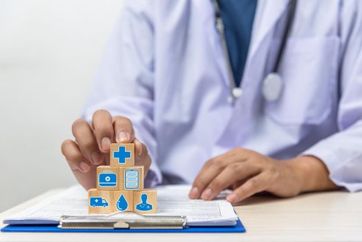 Hand holding wooden cubes block with insurance health car medical symbol on background and copy space.