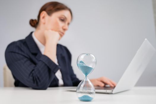 Business woman keeps track of time on an hourglass while working