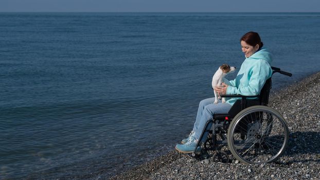 Caucasian woman in a wheelchair with a dog at the sea