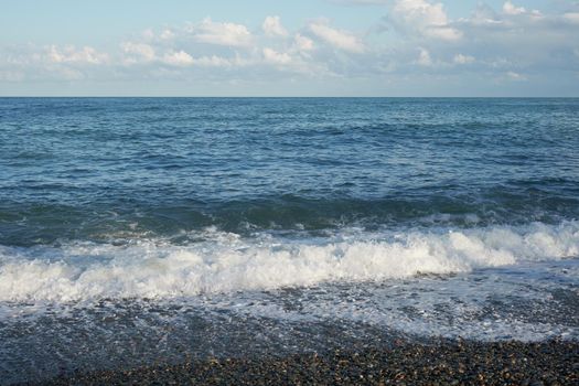 Sea shore with pebbles, wet sea pebbles on the beach and quiet sea surf. Restless sea and waves.