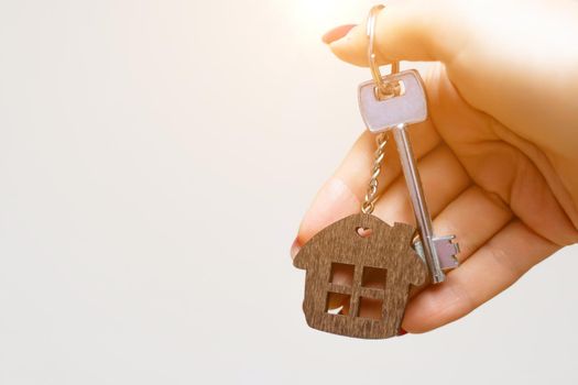 A woman's hand holds a house key on a white background with copy space. Real estate agent. Buying a house, apartment