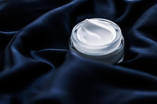 Beauty, anti-age cosmetics and skincare concept - Luxury face cream jar on a dark blue silk