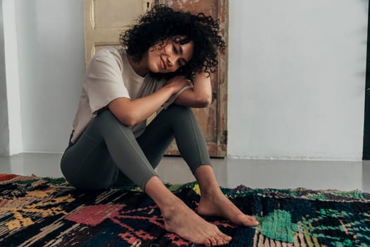 Smiling young multiracial woman sitting on the floor at home looking at camera. Copy space. Lifestyle concept.