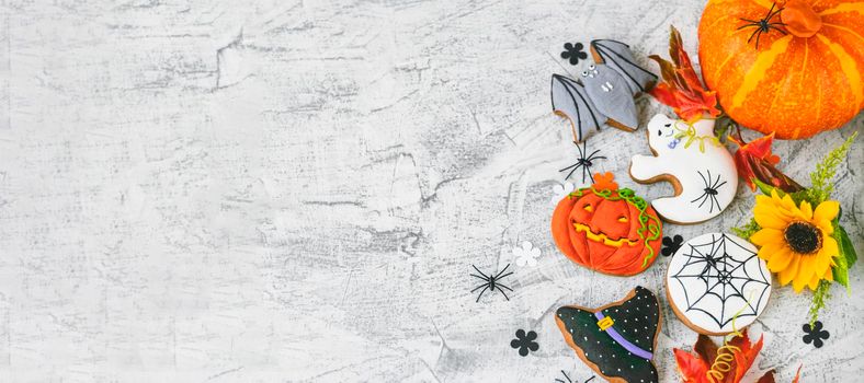 banner with Halloween background with cookies, leaves, sunflower and spiders, top view. Halloween objects on textured concrete with space for text. Flat lay. Soft focus